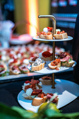 A variety of appetizers, including bruschetta, are displayed on a tiered serving stand. Perfect for catering, event promotions, or upscale dining, showcasing an elegant appetizer spread.
