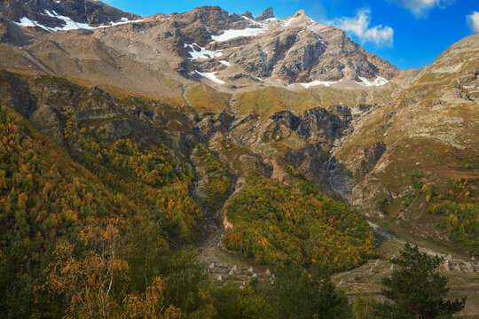 Rocky autumn mountains with melting snow on the top. On the slope avalanche control structure - concrete avalanche cutters. Background image.