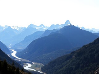 A breathtaking view of majestic snow-capped mountains surrounded by lush greenery and flowing rivers, greenery, nature