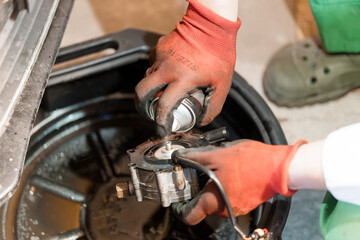 Obraz premium Detailed Mechanic Repair Process of a Car Component in a Workshop Setting