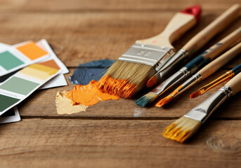Fototapeta premium Tools for creativity on a wooden surface with paint swatches, brushes, and vibrant colors in an artist's workspace