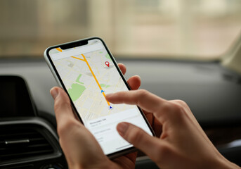 A person navigating with a smartphone in a car while following directions in an urban area during the daytime