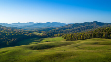 Naklejka premium Sweeping drone footage of rolling hills and distant mountains under a clear blue sky