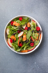 Fresh vegetable salad plate of  papaya, leaves raspberry and apple. Healthy food. Diet dinner or lunch menu. Salad plate on table. Flat lay.