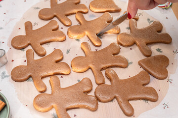 Making Christmas cookies - gingerbread men, woman is cutting out the cookies with molds.