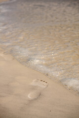 Footprints in the sand at the edge of the water in Topsail Hill Preserve, Santa Rosa Beach, Florida