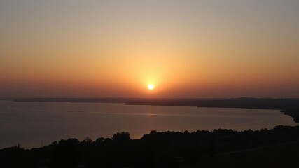 Obraz premium A stunning sunrise over a tranquil lake, casting a golden glow on the water and surrounding landscape, tranquil, sunlight