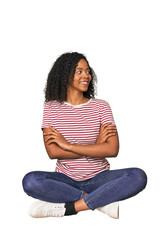 oung woman sitting on floor in studio smiling confident with crossed arms.