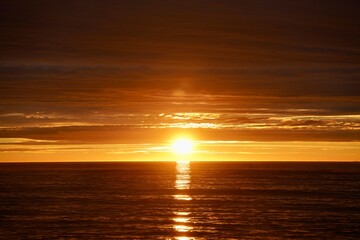 Horizon is coloured deep red as the sun sets in the ocean outside Vevang, Norway