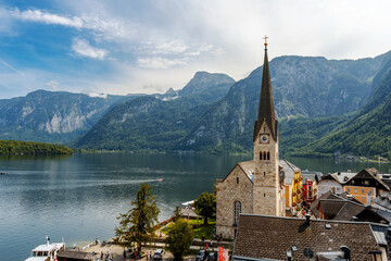 Famous Hallstatt mountain village with Hallstaetter Lake in the Austrian Alpes. Bell tower of village Protestant Parish Church and rooftops on foreground.