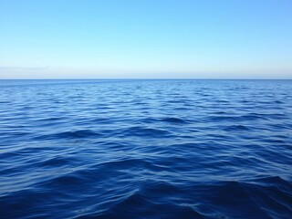 Obraz premium A serene ocean background with gentle waves and a clear blue sky, sky, background