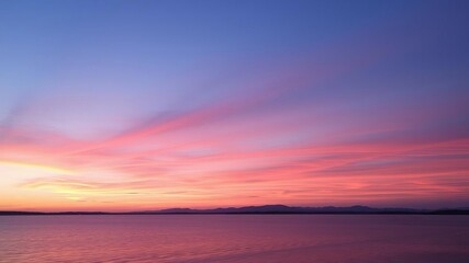 Naklejka premium A serene and tranquil image of a colorful sunset over a calm lake, with the sky painted in hues of orange, pink, and purple, reflecting off the water below, serene, reflection