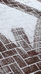 Snow tyre mark. Asphalt covered in snow. Dangerous road conditions. Car imprint on frozen ground. Tire trail on ice. City streets covered in snow during heavy snow fall. Slippery road background.