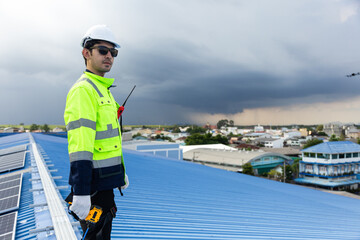 Engineer worker standing on the factory roof checking on solar cell or photovoltaic panel...