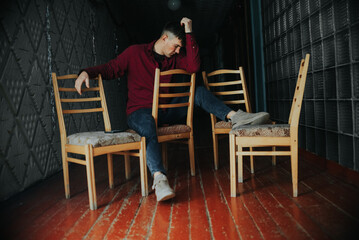 Stylish Man Posing with Chairs in Industrial Setting