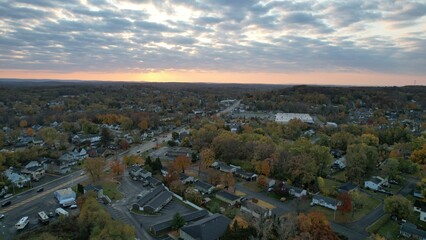 Fototapeta premium Aerial view of a suburban neighborhood with autumn foliage under a dramatic sunset sky