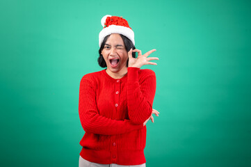 An Asian woman in a red sweater and Santa hat, smiling and making an 