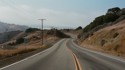 A winding road stretches through rolling hills under a vast sky, offering a sense of freedom and adventure in an open landscape.