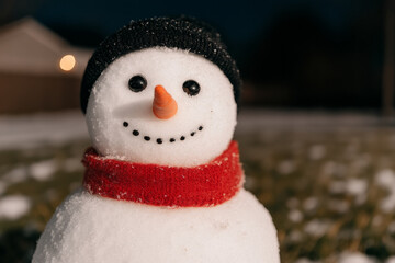 Obraz premium A snowman with a red scarf and a black hat is smiling