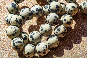 Beautiful round beads of spotted Dalmatian jasper in macro photography, perfect for crafting and jewelry design. Decorative round stone beads of white colors with black spots for boho jewelry design.