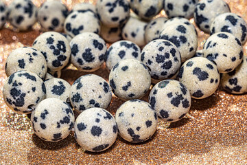 Obraz premium Beautiful round beads of spotted Dalmatian jasper in macro photography, perfect for crafting and jewelry design. Decorative round stone beads of white colors with black spots for boho jewelry design.