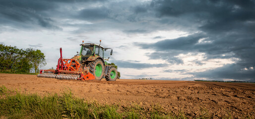 Obraz premium Tracteur labourant les champs dans la campagne de France au printemps.