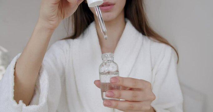 Woman open serum with pipette. Natural beauty products. Mineral organic oil. Eco cosmetic cream, Woman applying serum. Anti aging or glowing skin. Young woman applying rejuvenating serum on body.