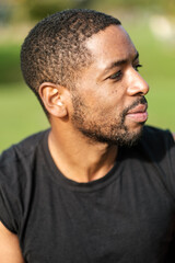 Young black man wearing black t-shirt looking away in a park