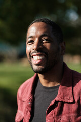 Portrait of smiling young man wearing red corduroy jacket in park