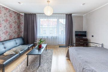 Home Living Room and Bedroom. Windows, Balcony, Stylish Retro Style Apartment. Open Space Interior, Sofa, Couch and Double Bed. Hardwood Floor and Carpet. Coffee table and Flower.