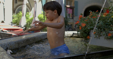 Young boy jumping into water, splashing energetically in a stone fountain, celebrating summer...