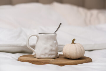 A warm mug of rich cocoa with a small pumpkin creates a cozy autumn vibe in a charming bedroom atmosphere