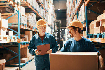 Supervisor and warehouse worker discussing logistics while checking inventory