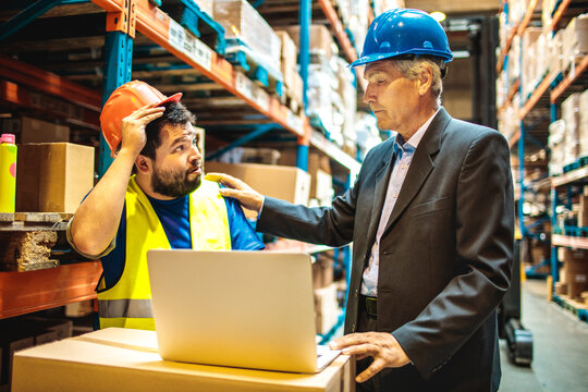 Warehouse worker discussing logistics with manager over a laptop