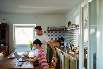 Couple managing bills with laptop on kitchen desk at home