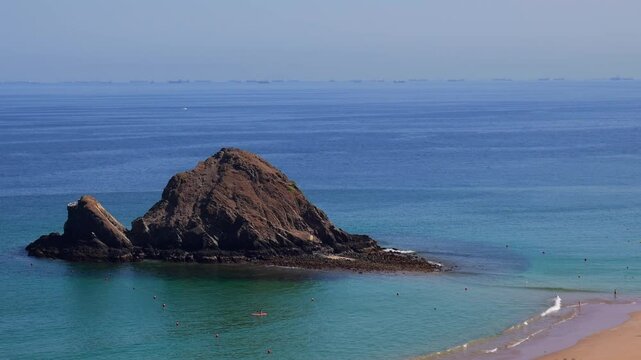 Snoopy Island in Fujairah, UAE. Aerial view of the beach with turquoise waters, a rocky island and a resort nearby