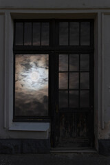 Fototapeta premium View of the full moon among the clouds through a closed window