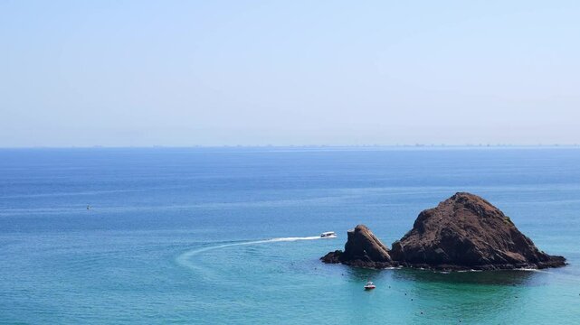 Snoopy Island in Fujairah, UAE, viewed from the coast with clear blue waters surrounding the rocky island