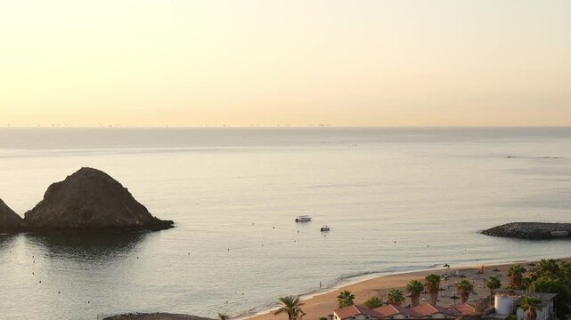 Snoopy Island in Fujairah, UAE. Aerial view of the beach, rocky island and a resort nearby at sunset