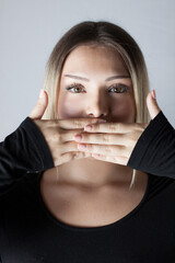 young woman holding her hands in front of her mouth