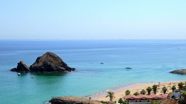 panorama of Snoopy Island in Fujairah, UAE. Aerial view of the beach with turquoise waters, a rocky island and a resort nearby