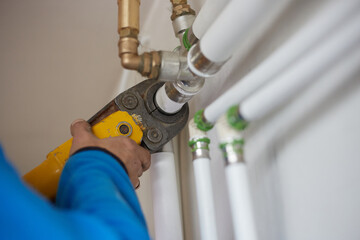 A worker connects pipes. Hand press for the water industry.
