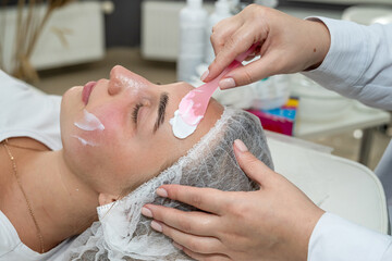 Beautiful young girl receive nourishing cream on here face, spa procedures