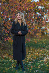 Blonde hair lady in black wool coat and golden scarf, fashionable trends for women, real photo outdoor portrait