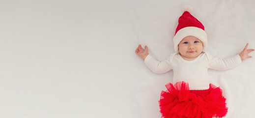 Baby girl in a Santa hat on a light background.holiday.