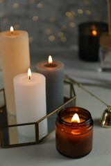 Beautiful burning candles on table against blurred lights, closeup