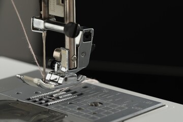 Sewing machine with thread on dark background, macro view. Space for text