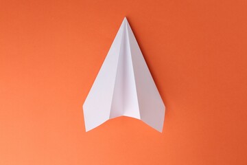 One handmade paper plane on orange background, top view