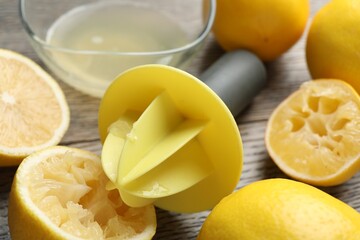 Plastic juicer and fresh lemons on grey wooden table, closeup
