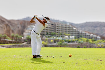 Fototapeta premium The golfer hits the golf ball with the Drive in his hand, on the tee.